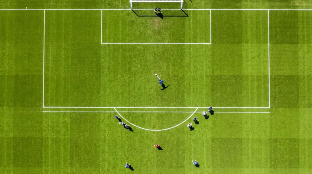 Campo da calcio visto dall'alto con linee del campo e area di rigore in evidenza durante una partita